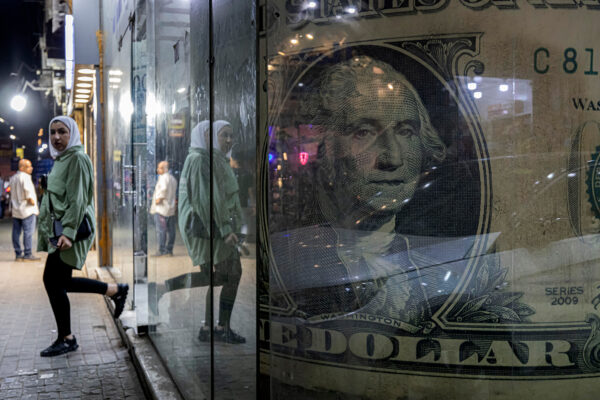 A woman walks out of a currency exchange shop displaying a giant U.S. dollar banknote in Cairo. © Khaled Desouki/AFP/Getty