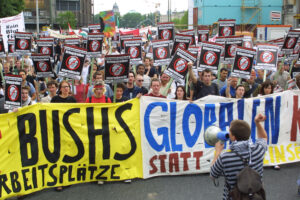 Demonstrators carry signs reading "No Attack Against Iraq - Warmongers Not Welcome" with a portrait of U.S. President George Bush in Berlin on May 21, 2002. © Sean Gallup/VISUM/Redux