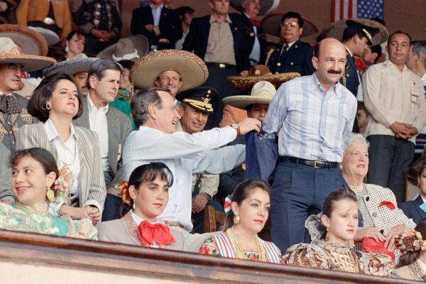 U.S. President George Bush helps Mexican President Carlos Salinas de Gortari remove his jacket at a rodeo in Agualeguas, Mexico, on November 26, 1990. © Marcy Nighswander/AP