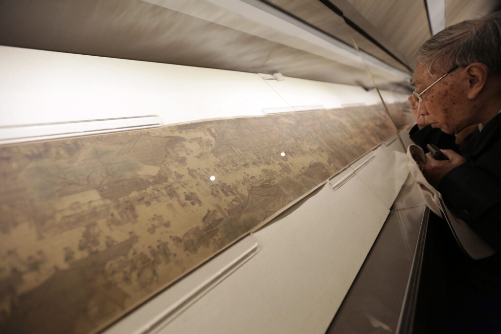 A visitor studies the scroll painting “Along the River During the Qingming Festival” at Beijing's Palace Museum. © How Hwee Young/EPA/Shutterstock