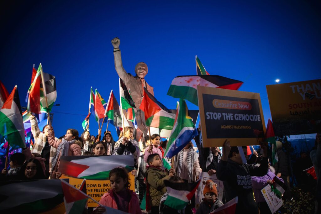 Palestinians carrying flags and banners gather in Nelson Mandela Square in Ramallah, West Bank, on January 10, 2024, to demonstrate support for the case filed by South Africa against Israel at the International Court of Justice. © Issam Rimawi/Anadolu/Getty