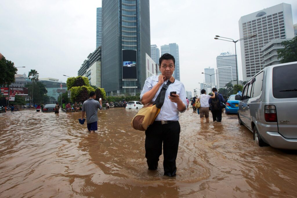 People wade through floodwaters in Jakarta's central business district in 2013. © Ed Wray/Getty