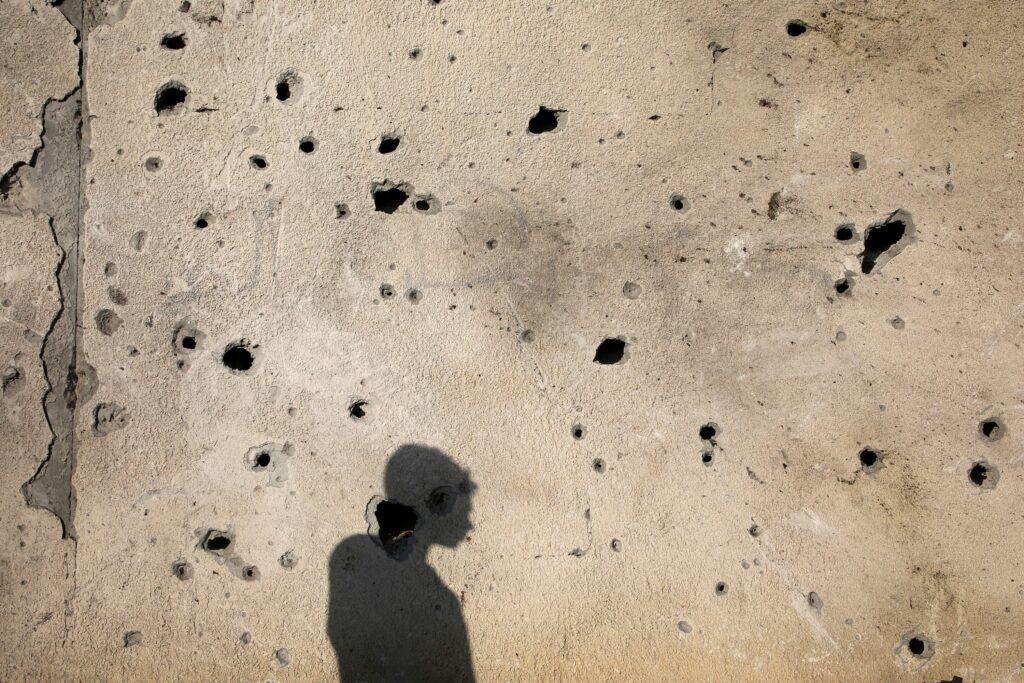 A Palestinian casts a shadow on a damaged wall outside a school sheltering displaced people in Khan Younis in the southern Gaza Strip, July 10, 2024.