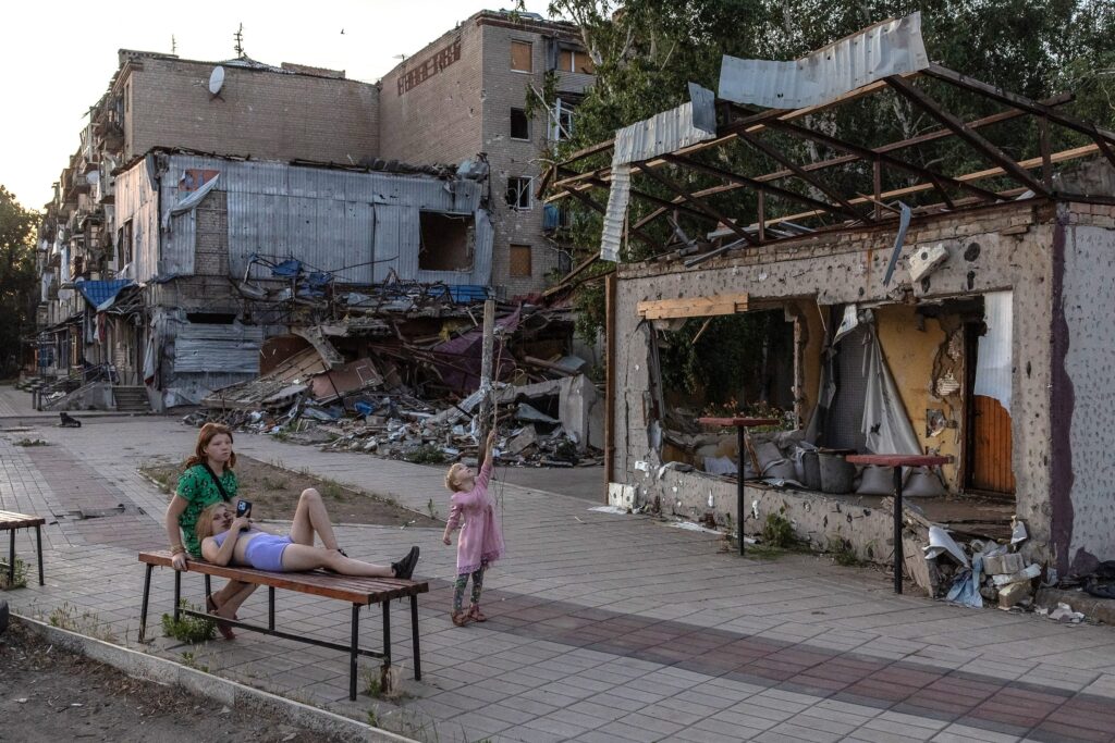 Young people sit in front of destroyed buildings in Kostyantynivka, Ukraine, on June 22, 2024. © Roman Pilipey/AFP/Getty