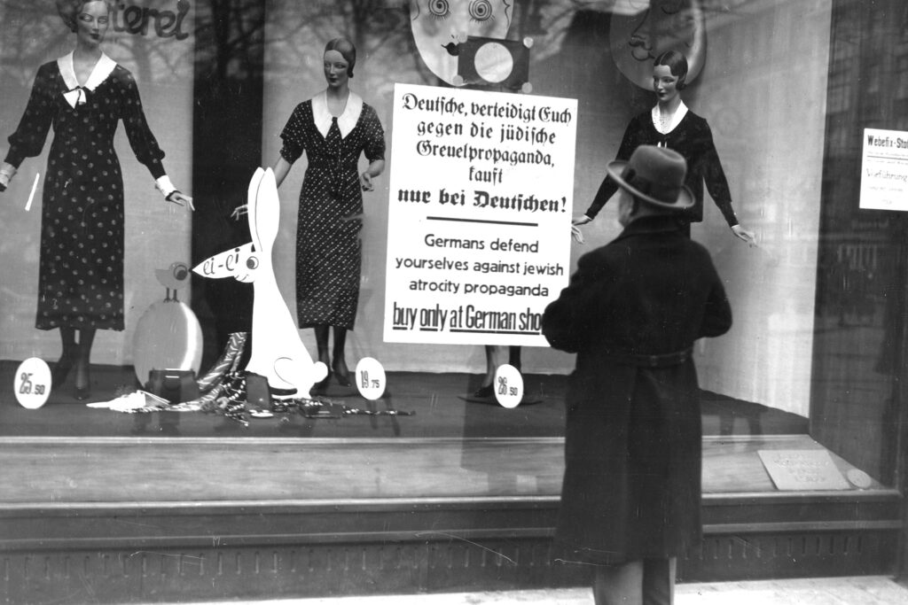 A man reads a Nazi sign posted on a Jewish-owned shop window in Berlin, Germany before the start of WWII. © Visual Studies Workshop/Getty