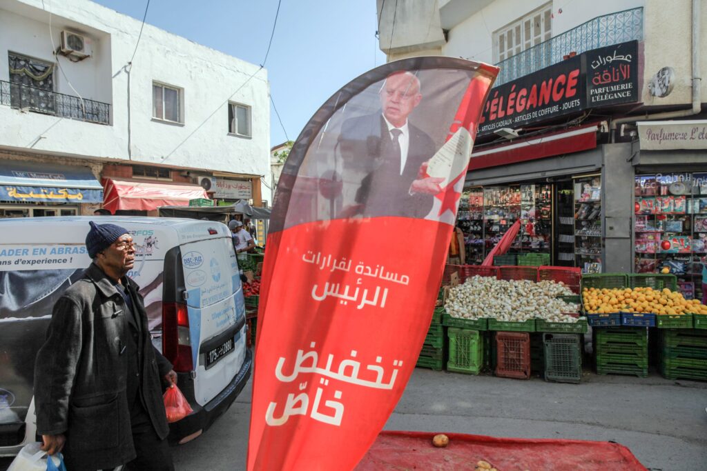 A banner with an image of Tunisian President Kais Saied, which reads in Arabic; "a special discount in support of the president's decisions," is set up in front of a shop in Ariana, Tunisia, on April 8, 2022. © Chedly Ben Ibrahim/Hans Lucas/Redux