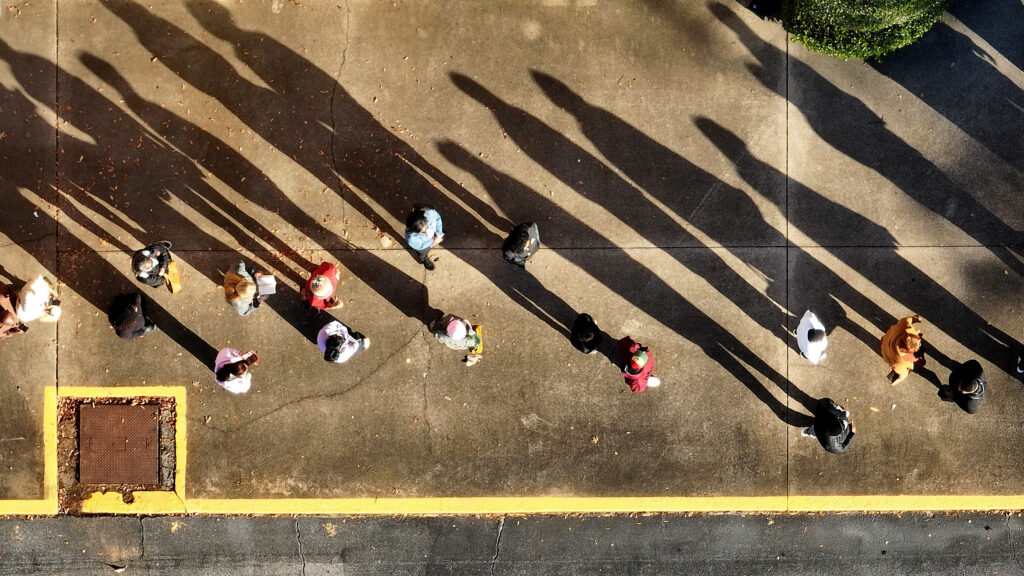 Voters cast long shadows while waiting in line to cast their ballots in Decatur, Georgia, on November 26, 2022. © Justin Sullivan/Getty