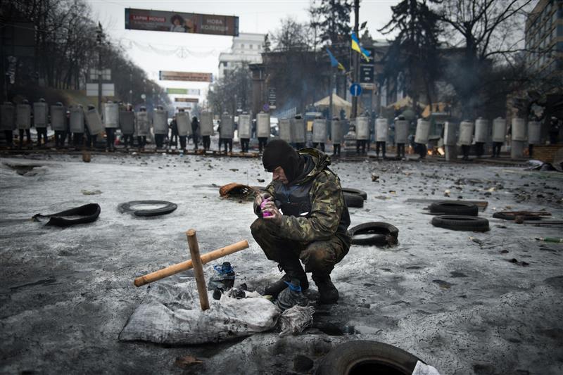 An anti-government protester lights a candle in front of riot police in Kyiv in 2014. © Martin Bureau/AFP/Getty